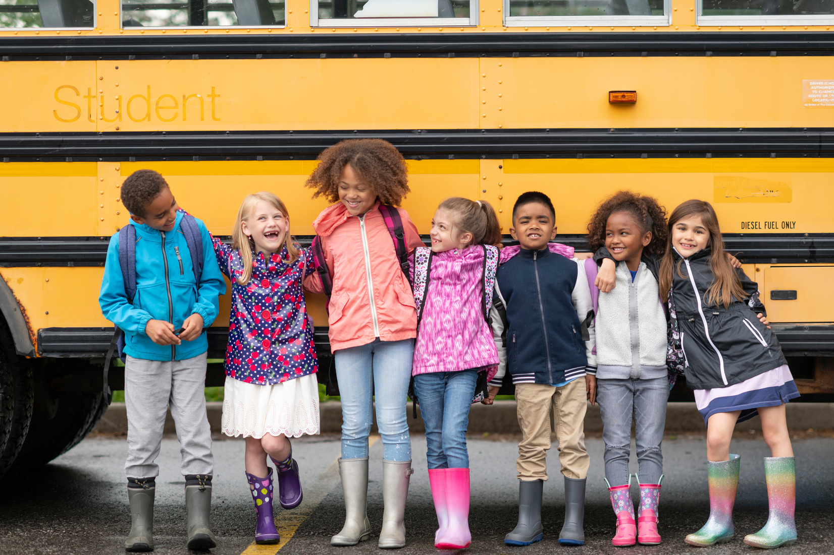 Happy group of kids standing by school bus